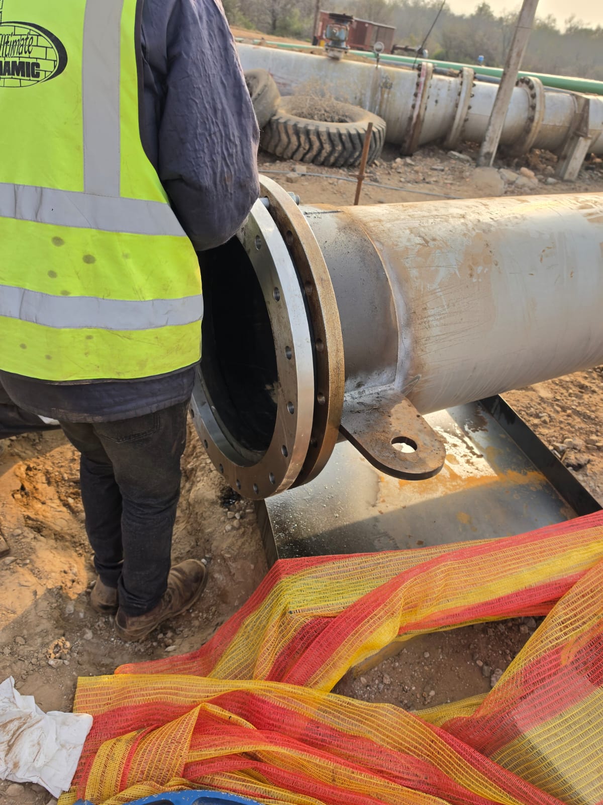 Lined steel slurry pipe flange being inspected during on-site installation